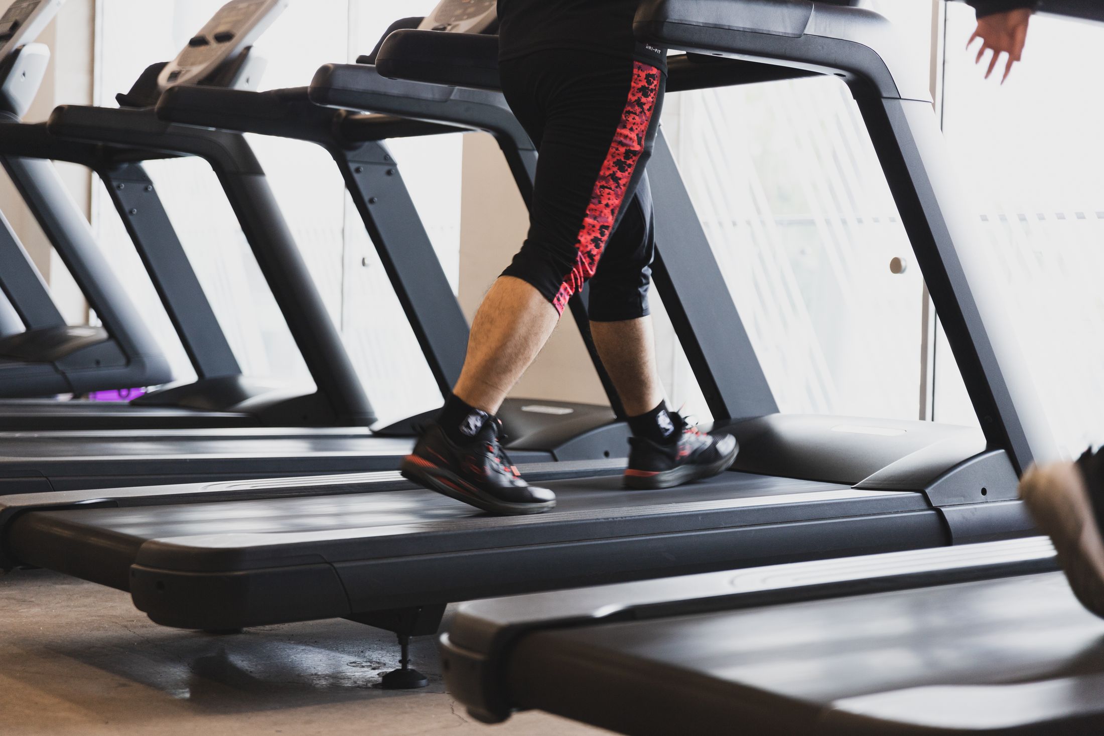 A member walking on a treadmill in a modern gym.